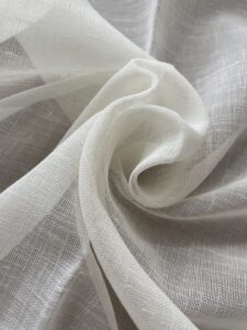 Close Up Of Sheer White Fabric With A Lightweight, Gauzy Texture, Folded Into Soft, Flowing Layers.