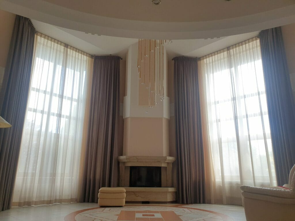 A living room with beige curtains and a fireplace.