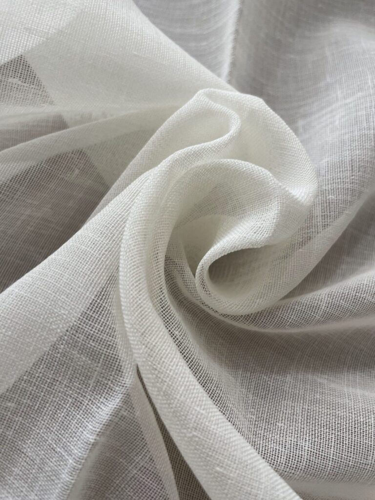 Close Up Of Sheer White Fabric With A Lightweight, Gauzy Texture, Folded Into Soft, Flowing Layers.