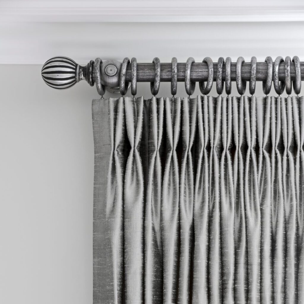Gray Pleated Curtains Hanging From A Decorative Metal Rod With A Spherical Finial, Against A Light Colored Wall.
